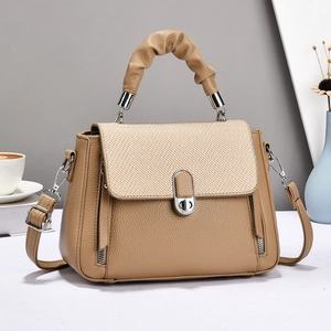 Detail showing khaki lychee texture bag with woven flap and decorative side zippers