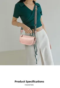 Dettaglio borsa a mezzaluna rosa chiaro con tracolla jacquard su camicetta verde