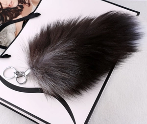 Macro shot of oversized black and silver real fox fur tail keychain with silver metal clip
