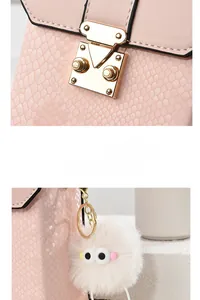 Detail of pink snake pattern crossbody bag featuring a gold square lock and white plush charm