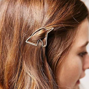 Detail view of a minimalist gold unicorn hollow metal hair clip worn on long brown hair