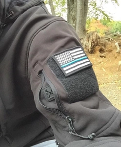 Detail of thin blue line USA flag patch on a black tactical jacket sleeve pocket