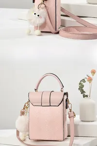 Detail of pink snakeskin pattern mini crossbody bag with cute plush monster charm