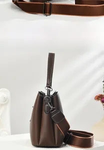 Detail der dunkelbraunen Leder-Eimertasche mit weißen Kontrastnähten und breitem Webgurt