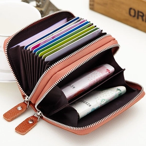 Macro detail of orange leather coin purse featuring dual zippers and multiple card slots