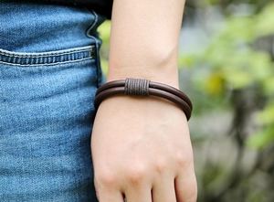 Close-up of a brown braided leather bracelet with double-cord design on a model wrist