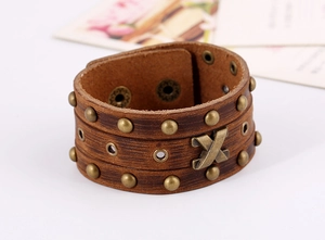 Detailansicht eines Vintage Lederarmbands in Braun mit Metallnieten und X-förmigem Akzent
