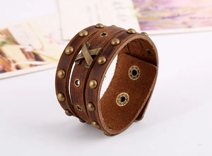 Detailansicht eines braunen Lederarmbands mit Messingnieten und X-förmigem Metallelement