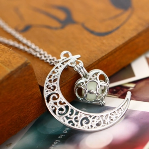Gros plan du collier lune évidé avec perle lumineuse dans sa cage en forme de cœur