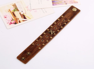 Detail eines Vintage-Punk-Lederarmbands mit Bronze-Nieten und Kreuz-Metallemblem