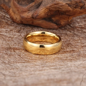 Polished gold tungsten ring on a textured natural background with premium wood accents