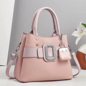 Détail d'un sac cabas tissé rose avec boucle luxueuse en strass et mini pendentif décoratif