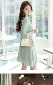 Gros plan d'un sac à main blanc cassé en cuir grainé avec une robe en mousseline vert menthe