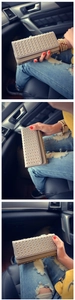 Detail of a chic cream studded clutch bag held inside a luxury car environment