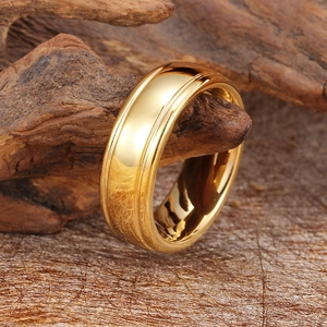 Polished gold tungsten steel ring for men hanging on a wooden stand in a warm setting