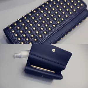 Detail view of navy rivet clutch showing gold studs, durable stitching, and phone compartment