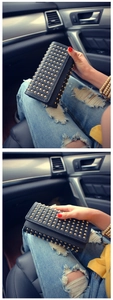 Detail of a black leather clutch with golden punk studs on a car interior background