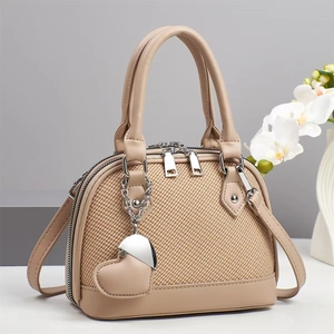Detail of light brown handbag with lychee pattern and heart-shaped metal pendant charm