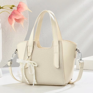 Détail du sac cabas beige avec texture tissée, pendentif perle et bandoulière amovible