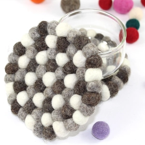 Macro shot of circular wool felt ball coaster with brown and white checkerboard pattern