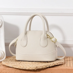 Sac à main beige en cuir grainé avec doubles poignées et détails dorés sur un tapis