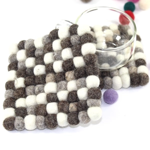 Macro shot of square wool felt coasters with white, grey, and brown checkered ball design