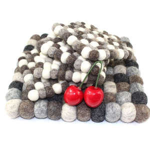 Handmade wool felt ball coasters in grey and brown checkered pattern for heat insulation