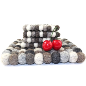 Detail of square wool felt coasters in white and grey colors with cherry decoration