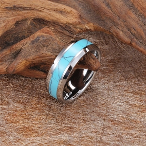Polished tungsten steel ring featuring turquoise inlay on a natural wood background