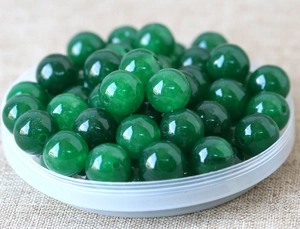 Macro shot of polished green jade beads on linen background for DIY jewelry making