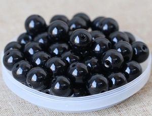 Macro detail of polished black round beads with center holes for DIY jewelry making
