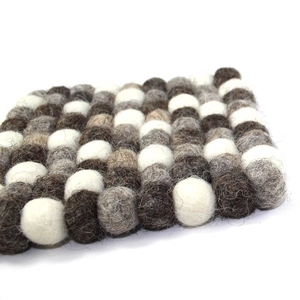 Detailed macro view of handmade wool felt ball coaster in brown and beige tones
