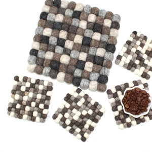 Flat lay of handmade wool felt ball coaster set in natural grey brown and white tones