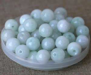 Macro detail of natural light green jade beads with threading holes for DIY jewelry