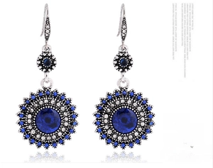Detailed close-up of retro bohemian sunflower drop earrings with navy blue gemstones