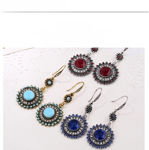 Detail of vintage bohemian sunflower drop earrings in ruby red, turquoise, and navy blue