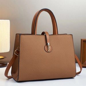 Brown textured leather crossbody tote bag with gold hardware shown in home setting