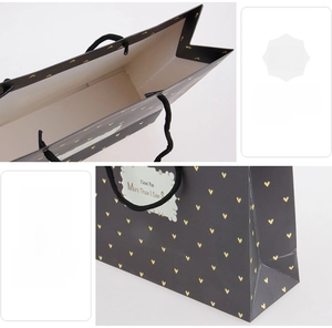 Detail of black gift bag showing reinforced base and black woven rope handle construction