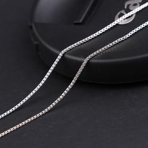 Close-up of a delicate silver box chain necklace with minimalist geometric weaving detail