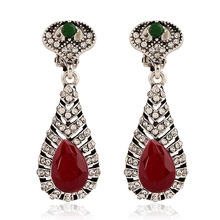 Detail of vintage bohemian drop earrings with red pear-shaped stones and green gems