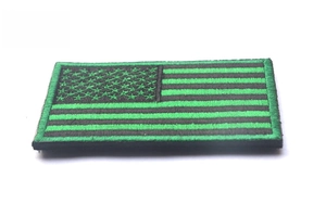 Close-up of black and green embroidered USA flag tactical patch with high density texture