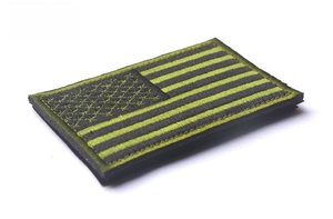 Detail of USA flag tactical patch with yellow-green embroidery and black hook-and-loop back
