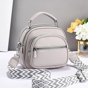 Close-up of a grey litchi leather handbag with multi-layer zippers and woven strap