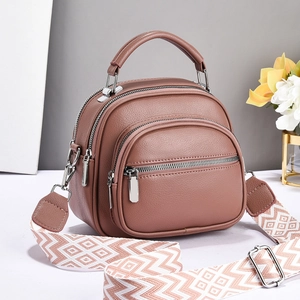 Close-up of brown PU leather handbag featuring multiple zippers and geometric strap