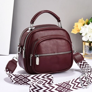 Detail of burgundy pebbled leather handbag with wide geometric patterned strap