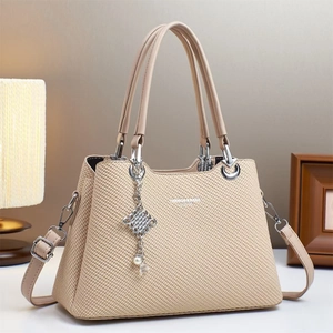 Close-up of beige woven canvas handbag with metal ring handles and pearl flower charm