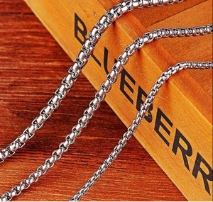 Detailaufnahme von drei silbernen Edelstahl-Boxketten in verschiedenen Größen auf Holz