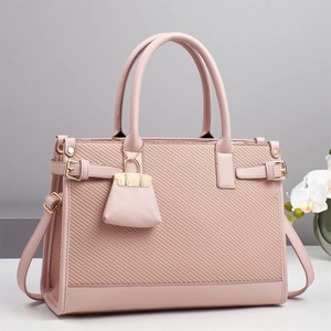 Detail of pink woven texture handbag with golden hardware and mini bag charm