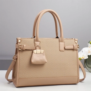 Detail of elegant beige woven handbag showing fine texture, leather trim and gold hardware