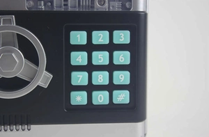 Detail of ATM toy piggy bank featuring mint green keypad and silver rotary wheel handle